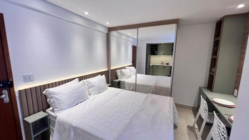 a bedroom with a white bed and a mirror at Loft novo e aconchegante perto do centro histórico in São João del Rei