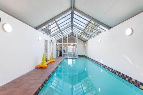 an indoor swimming pool with a glass ceiling at Handy CBD Covered Free Parking Gym 2 Bdrm in Christchurch