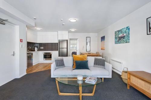 a living room with a white couch and a table at Handy CBD Covered Free Parking Gym 2 Bdrm in Christchurch
