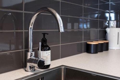 a bottle of soap sitting on a kitchen sink at Handy CBD Covered Free Parking Gym 2 Bdrm in Christchurch