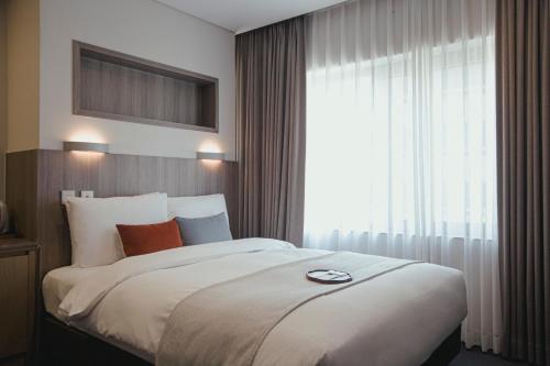 a bedroom with a large bed with a large window at Amid Hotel Seoul in Seoul
