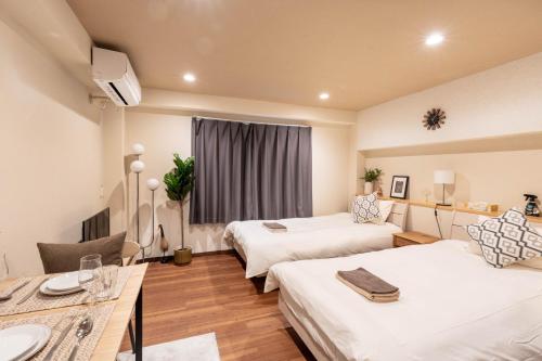 a hotel room with two beds and a table at Ostay Ikebukuro Dairaku Hotel Apartment in Tokyo