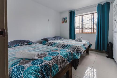 two beds in a room with blue curtains at Las Carmelas, Airport Juan Santamaría, Alajuela, San José in Alajuela City