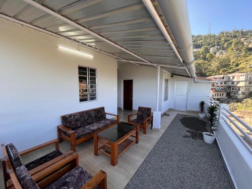 a room with couches and chairs on a balcony at Alpine Homestay in Kohīma