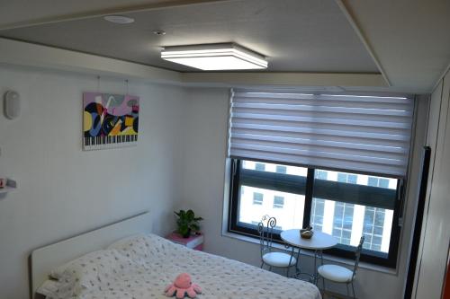 a bedroom with a bed and a window with blinds at For you House in Daegu