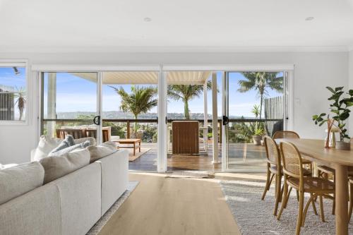 a living room with a white couch and a table at Chic Coastal 1-Bedroom Home with Balcony & BBQ in Deewhy
