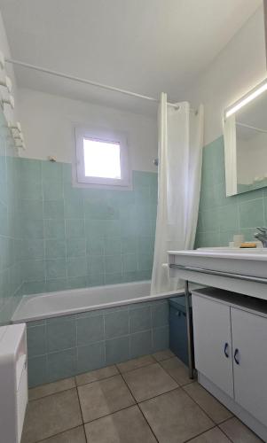 une salle de bain avec une baignoire et un lavabo dans l'établissement Charmant T3 avec Terrasse et Vue Panoramique sur le Golfe de Saint-Florent, à 300m de la plage de la Roya, à Saint-Florent