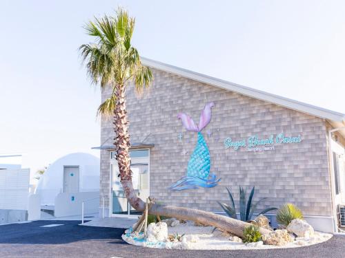 a building with a mermaid sign and a palm tree at Sugar Beach Oarai in Oarai