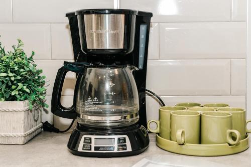a black blender sitting on a counter next to cups at Modern suite near Airport Hospital Henday Town Ctr in Nisku