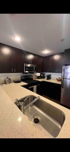 a kitchen with a stainless steel sink and wooden cabinets at Private Room and Bathroom in Los Angeles