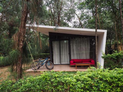 a red couch and a bench in a forest at Flamigo Dai Lai Resort - Villa Chủ Tự Doanh in Ngọc Quang