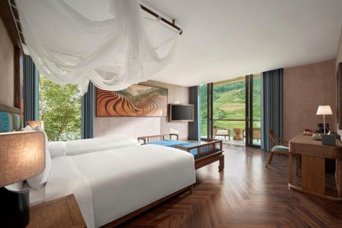 a bedroom with a white bed and a living room at Garrya Mù Cang Chải in Mù Cang Chải