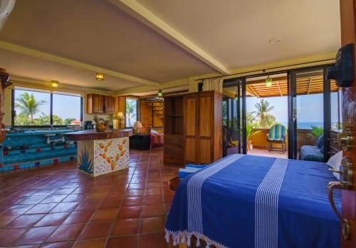 a bedroom with a blue bed and a view of the ocean at Hotel Casamar Suites in Puerto Escondido