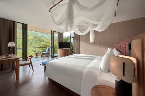 a bedroom with a large white bed and a living room at Garrya Mù Cang Chải in Mù Cang Chải