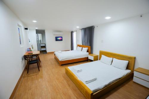 a hotel room with two beds and a desk at Blue Sea Luxury Hotel & Apartment Vũng Tàu in Vung Tau