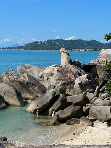 two people standing in the water on a rocky beach at Grand Rock Studio Samui in Lamai