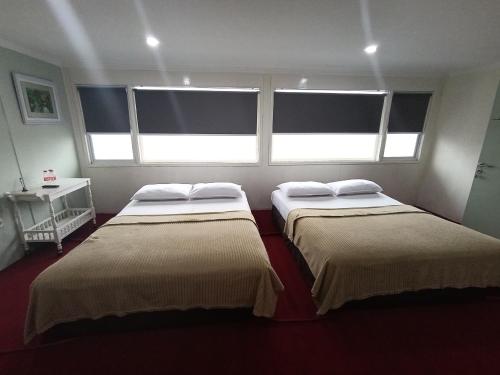 two beds in a room with two windows at Mamifokobo Guest House in Ciloto