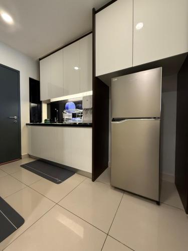 a kitchen with white cabinets and a stainless steel refrigerator at QUINCE HOME GRAND ION DELEMEN GENTING HIGHLANDs in Genting Highlands