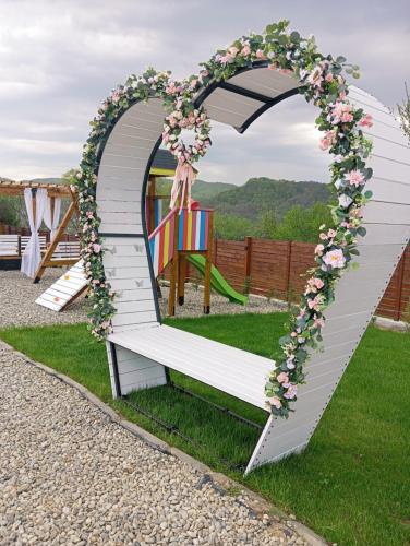 a heart shaped arch with a bench with flowers at Mareva House A Frame Chalet in Râmnicu Vâlcea