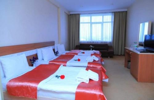 a hotel room with three beds with red and white sheets at Gabala Tufandag City Hotel in Gabala