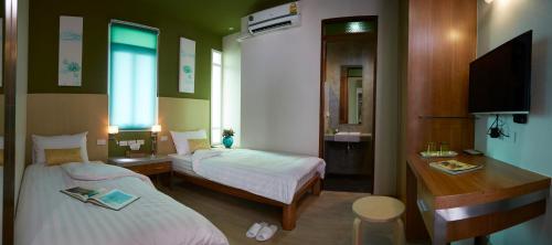 a bedroom with two beds and a desk and a television at Uncle Loy's Boutique House in Bangkok