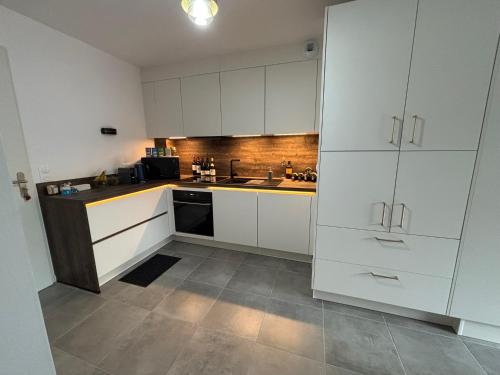 une cuisine blanche avec des armoires blanches et un évier dans l'établissement Agustina, à La Celle-sous-Gouzon