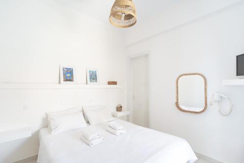 a white bedroom with a white bed and a mirror at Theo Studios & Apartments in Spetses