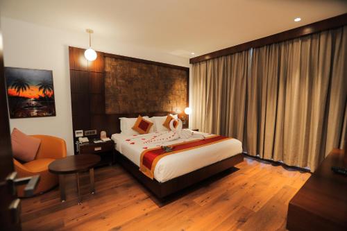 a hotel room with a large bed and a chair at Saugandhika West Gate in Wayanad