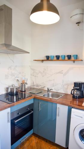 une cuisine avec des armoires bleues et un évier dans l'établissement Les Matelots Rouen Centre by MyFrenchPAT, à Rouen