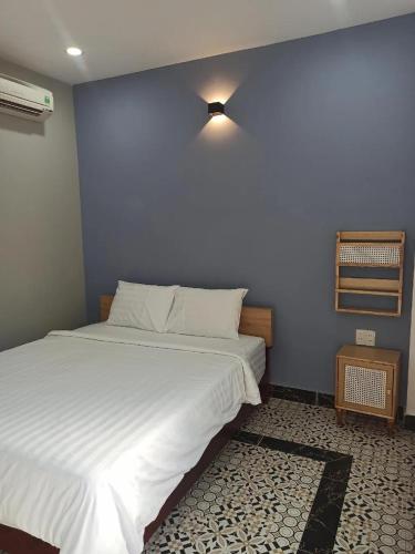 ein Schlafzimmer mit einem großen weißen Bett und einer blauen Wand in der Unterkunft Familia Resort in Phu Quoc