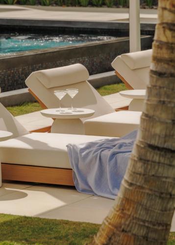 a row of lounge chairs and a table with wine glasses at One&Only Le Saint Géran, Mauritius in Belle Mare