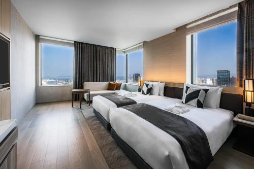 two beds in a hotel room with large windows at The Gate Hotel Fukuoka by Hulic in Fukuoka