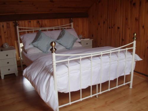 a white bed in a room with wooden walls at Cozy Home in Langeac
