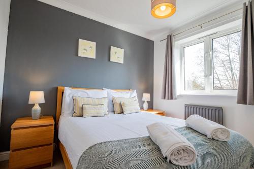 a bedroom with a bed with white sheets and a window at Stylish 3-Bed, Garden & Secure Parking - M5 5 mins in Hindlip
