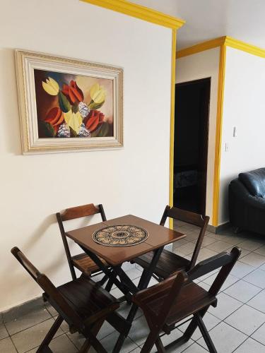 a table and chairs in a living room with a painting at Apartamento próximo ao mar in Maceió