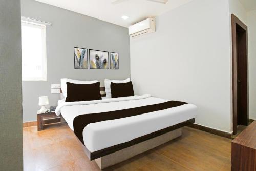 a white bedroom with a large bed in it at Super Townhouse Mancheswar Industrial Estate in Bhubaneshwar