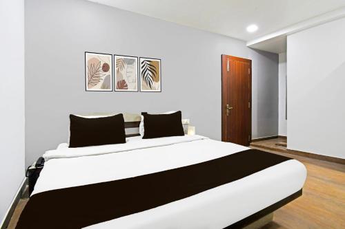 a bedroom with a large white bed with black pillows at Super Townhouse Mancheswar Industrial Estate in Bhubaneshwar