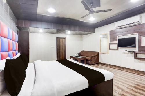 a bedroom with a bed and a chair and a television at Super Townhouse Haibowal Chowk in Ludhiana