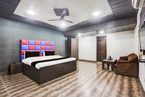 a bedroom with a large bed and a chair at Super Townhouse Haibowal Chowk in Ludhiana