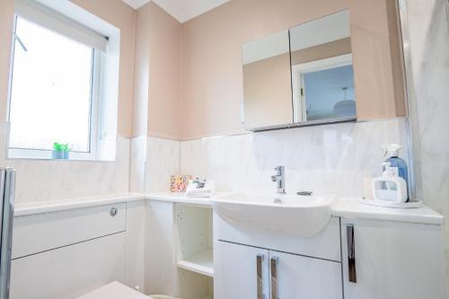 a white bathroom with a sink and a mirror at Stylish 3-Bed, Garden & Secure Parking - M5 5 mins in Hindlip