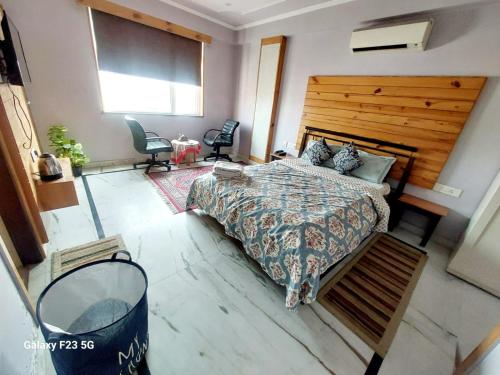 a bedroom with a large bed with a wooden headboard at Jaipur The Lodge B&B in Jaipur