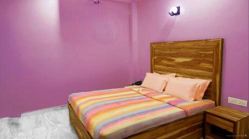 a purple bedroom with a bed with a wooden headboard at Arya beach Resort with Pool in Jāmb