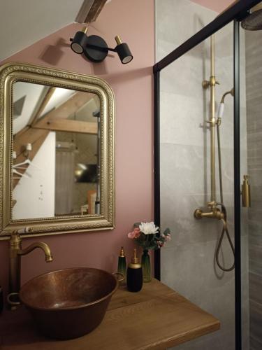 La salle de bains est pourvue d'un lavabo en cuivre et d'un miroir. dans l'établissement La Réserve, Suite et SPA, à Noyelles-sous-Bellonne