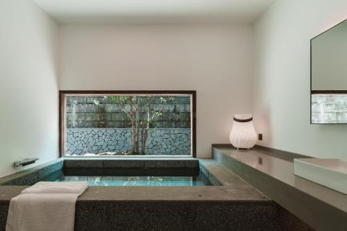 a bathroom with a tub and a sink and a window at YunXi ChanYi Hot Spring Hotel in Emeishan