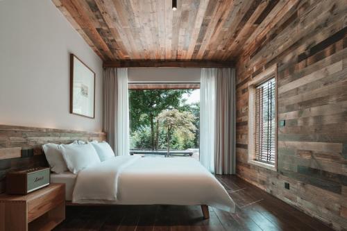 a bedroom with a large white bed and a window at YunXi ChanYi Hot Spring Hotel in Emeishan