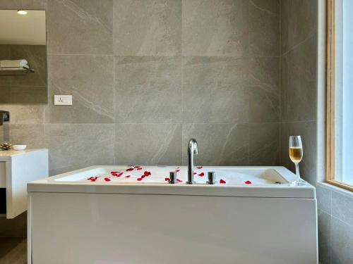 Una bañera con lavabo y una copa de vino. en Bookmark Resorts, Manali, en Manali