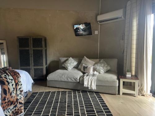 a living room with a couch and a tv on the wall at Simba Safaris African Pride Exotic Lodge in Lephalale