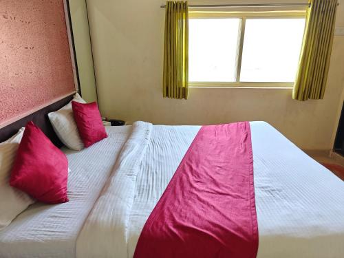 a bedroom with a bed with pink pillows and a window at Nisarga Lake Resort Tapola in Satara