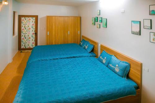 a bedroom with a large blue bed with blue pillows at Tôm Ti House - Mộc Châu in Mộc Châu