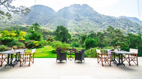 a patio with tables and chairs with mountains in the background at Rosewood Manor in Botiyatenna